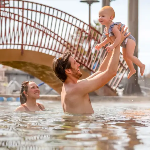 A family playing in a swimming pool outdoors.