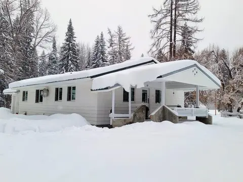 A white house covered in snow surrounded by snowy trees.