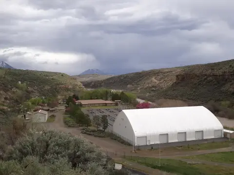 An aerial view of a facility with large buildings nestled in a valley under a cloudy sky.