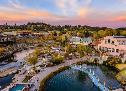 A resort with hot springs sits along a river at sunset.