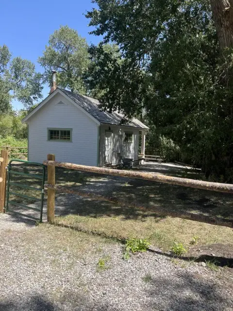 A small white building stands behind a wooden fence.