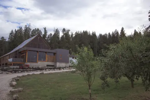 An exterior view of a large wooden building with a forest in the background.