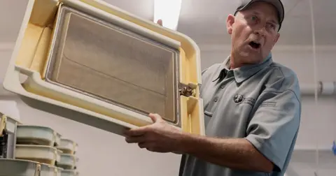 A man holds up a piece of equipment indoors.