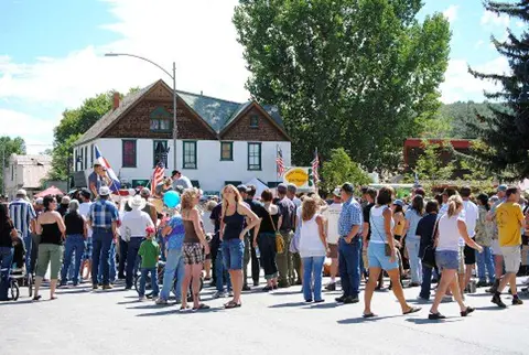 A crowd of people gathers outside a historic building on a sunny day.
