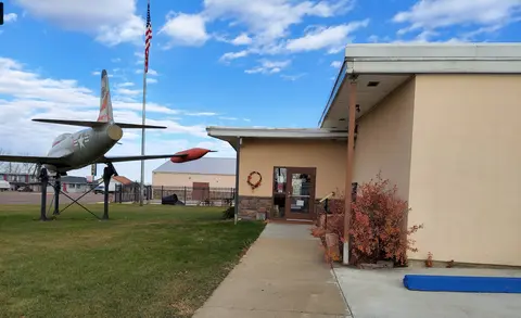 An exterior view of a building with an airplane monument on the lawn.