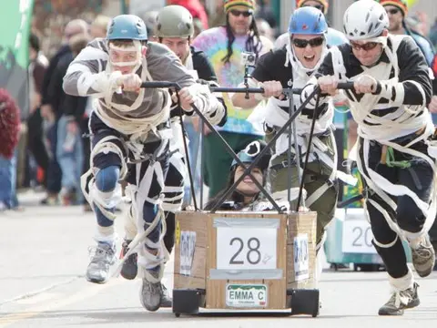 People push a soapbox car in a race.
