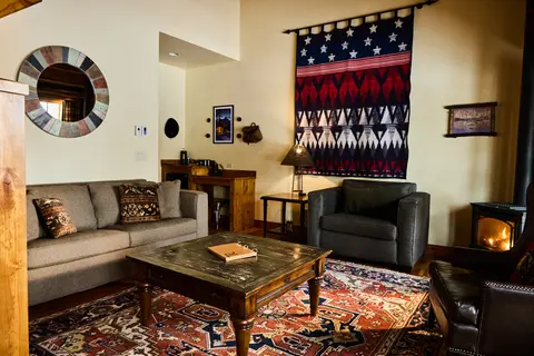 A cozy living room with a couch, armchairs, a coffee table, and a fireplace.