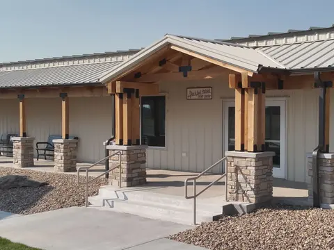 A modern metal building exterior with a covered entryway and stone-base pillars.