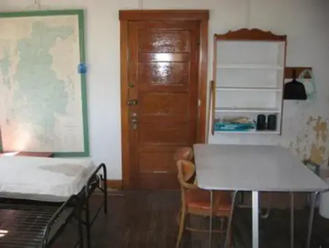 An interior view of a room with a wooden door, table, and shelving unit.