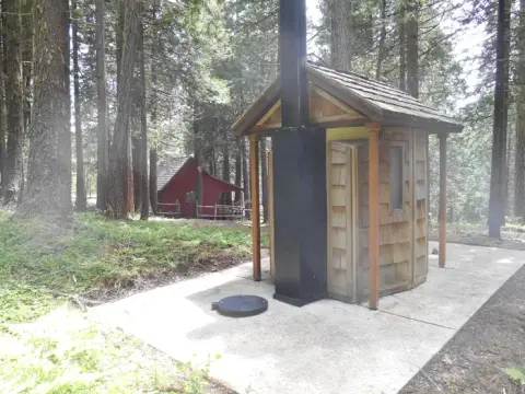An outdoor restroom structure in a forest.