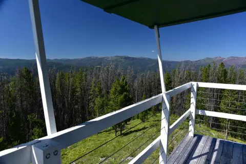 A view of forest and mountains from the balcony of a tower.