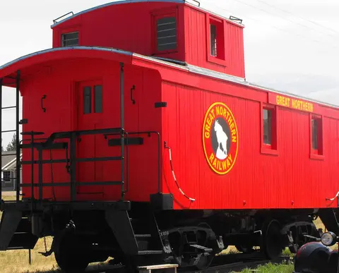 A red caboose with the railway logo sits outdoors.