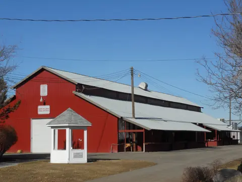 A large red barn with a white roof under a blue sky.