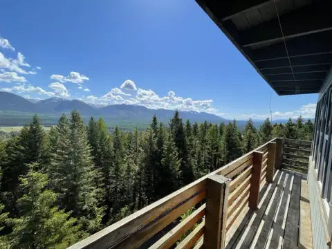 A view of a mountain landscape and forest from a wooden balcony.