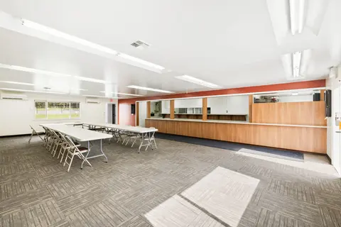 An interior view of a community room with tables, chairs, and a service counter.