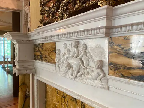 An ornate marble fireplace with relief carvings of cherubs.