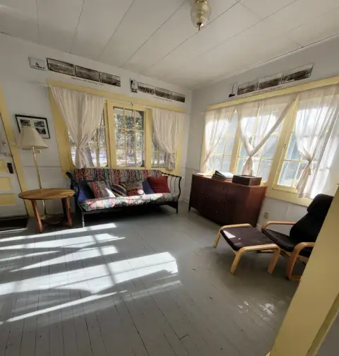 An interior view of a room with a couch, windows, and framed photos on the wall.