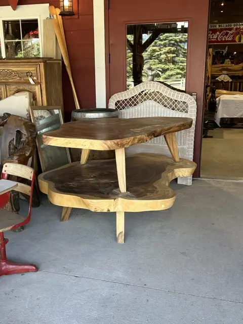 A unique wooden table on display outside a store entrance.