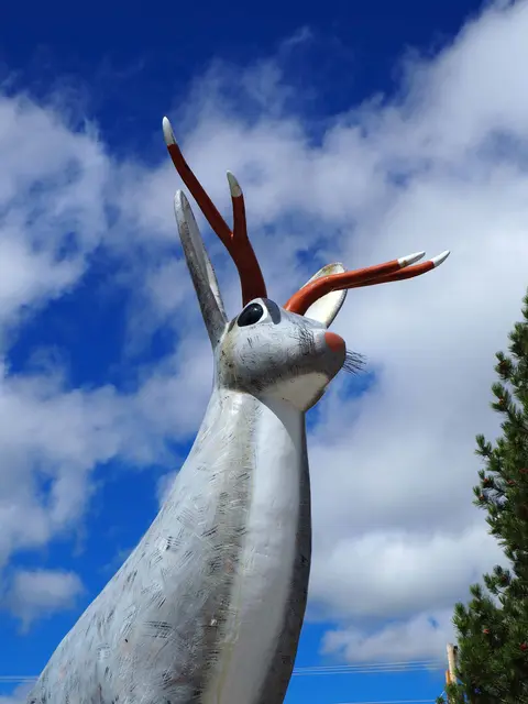 A large jackalope statue stands against a cloudy blue sky.