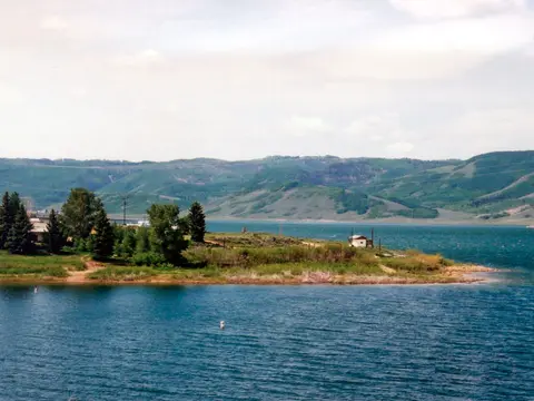 A scenic landscape view of a large body of water surrounded by green hills and trees.