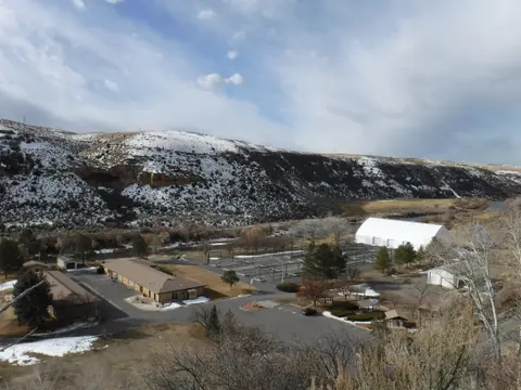An aerial view of a facility nestled in a valley with snow-capped hills.
