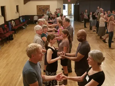 People participating in a group dance inside a hall.