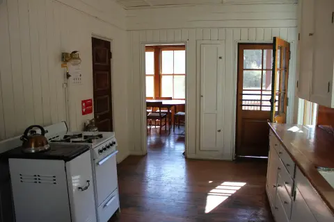 An interior shot of a rustic kitchen with white paneling and a wood floor.