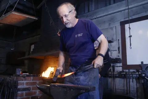 A person working at an anvil inside a workshop.