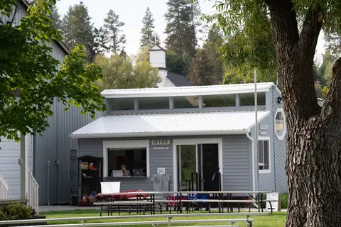 An exterior view of a small grey office building with a white metal roof.