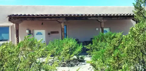 An exterior view of a building with a covered porch and green bushes.