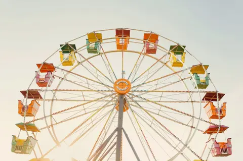 A colorful Ferris wheel stands against a pale sky.