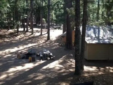 A small cabin and picnic table in a forest.