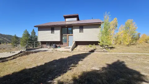 Exterior view of a two-story building in a rural setting with trees and a clear blue sky.