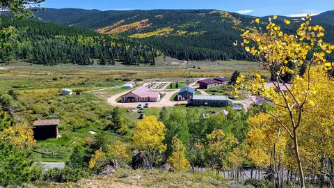 High-angle view of a facility in a mountain valley surrounded by trees with autumn foliage.