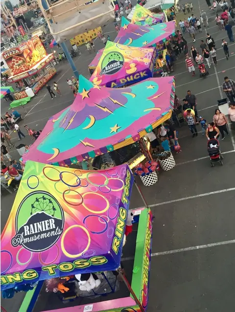 A high-angle view of colorful carnival booths and people walking around a fair.