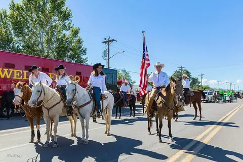 A group of people on horseback carrying an American flag in a parade.