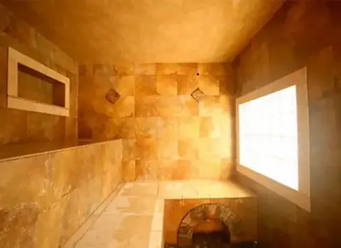 An interior view of a tiled room with a stone finish and a glowing window.
