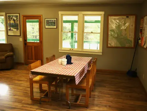 A table with a red-and-white checkered tablecloth inside a room with wooden floors.