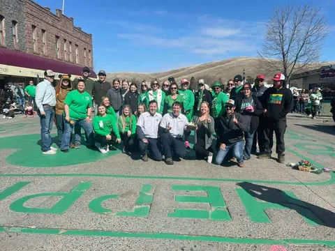 A large group of people pose for a photo on a painted street outdoors.