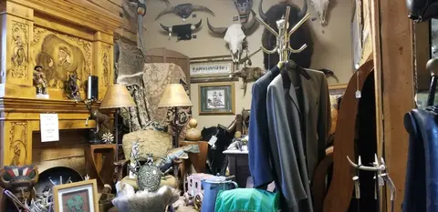 An interior shot of an antique or western-themed shop filled with various items and clothing on a rack.