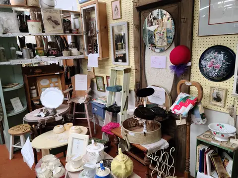 An interior view of a shop filled with antique items, mirrors, and home decor.