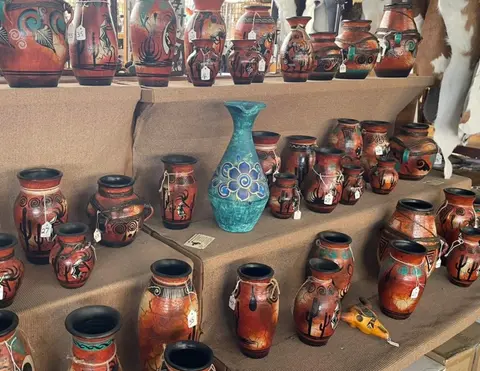 A display of numerous decorated pottery vases on tiered shelves.