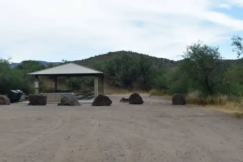 A covered picnic pavilion in a desert landscape with large boulders.