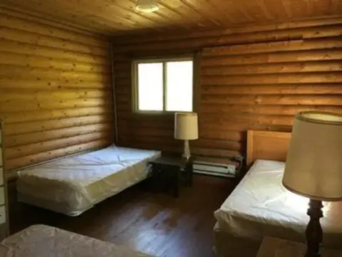 A rustic bedroom with log walls and multiple twin beds.