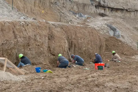 People working at an outdoor archaeological dig site.