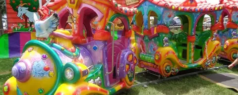A brightly colored amusement park train ride stands outdoors.