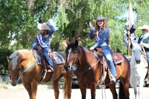 People ride horses outdoors during an event.