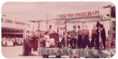 An old photograph shows a parade float with people on it.