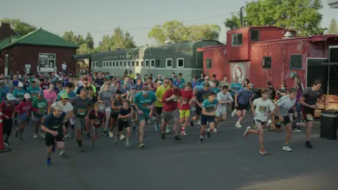 A large group of people participate in a running event outdoors.