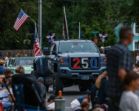 A decorated pickup truck participates in a parade while a crowd watches from the street.